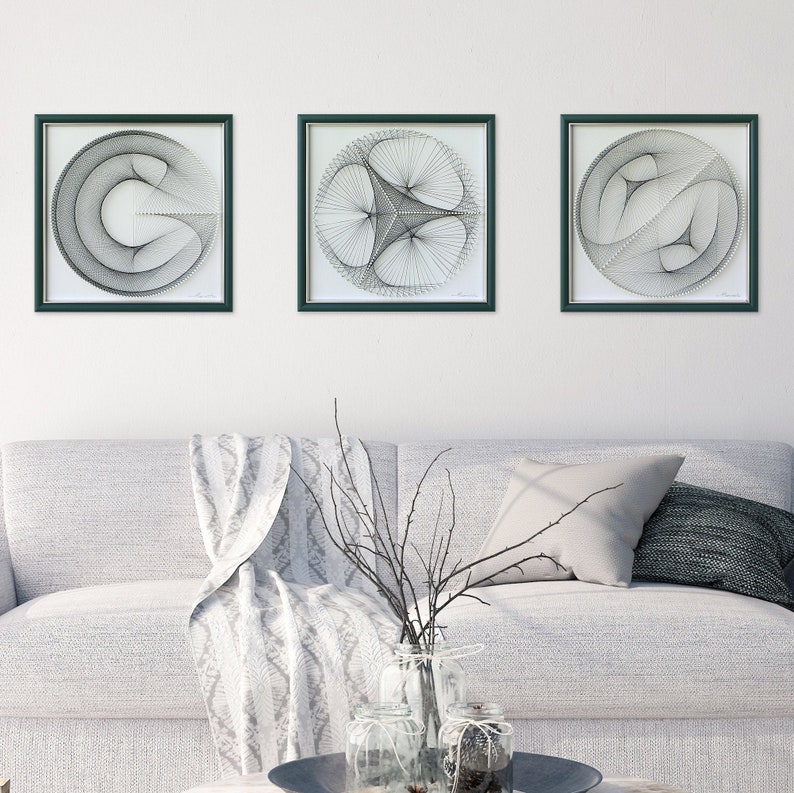 Puede incluir: Tres piezas de arte de cuerda en blanco y negro enmarcadas con dise&ntilde;os geom&eacute;tricos. Los marcos son de color verde oscuro y el fondo es blanco.