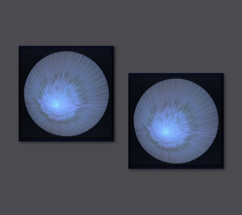 May include: Two framed black and white abstract art prints with a blue and white circular design. The circular design is made up of thin lines radiating from the centre.