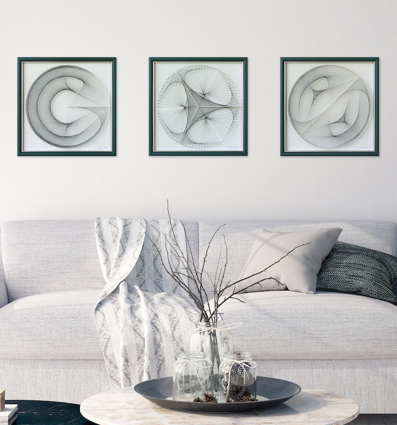 Puede incluir: Tres piezas de arte de hilo en blanco y negro enmarcadas con dise&ntilde;os geom&eacute;tricos. Los marcos son de color verde oscuro y el fondo es blanco.