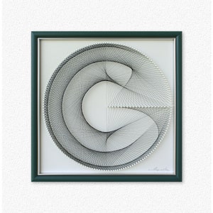 Puede incluir: Una pieza de arte de hilo en blanco y negro enmarcada en un marco verde oscuro. El arte de hilo representa un c&iacute;rculo con una l&iacute;nea curva en su interior, creando un dise&ntilde;o geom&eacute;trico. La pieza est&aacute; firmada "L. Saputo" en la esquina inferior derecha.