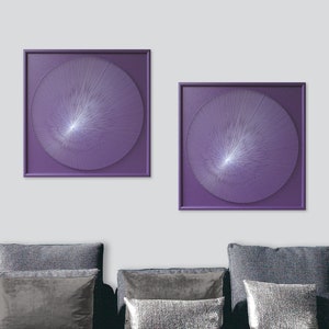 May include: Two square framed wall art pieces with a purple background and a white circular design in the centre. The design is made of thin lines radiating from the centre.