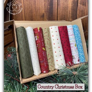 Può includere: Una scatola piena di sette rotoli di tessuto con diverse stampe a tema natalizio. Le stampe includono fiocchi di neve rossi e verdi, pois rossi e bianchi, una stampa verde con le parole "Meet me under the mistletoe" e "Over the river", e una stampa blu con le parole "Merry Christmas".