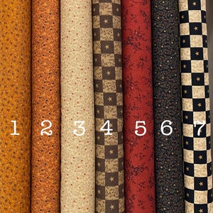 Può includere: Una collezione di sette rotoli di tessuto con vari motivi. I tessuti presentano disegni floreali, a stella e a scacchi in colori come oro, arancione, beige, marrone, rosso, blu navy e nero. Ogni rotolo è numerato da 1 a 7.