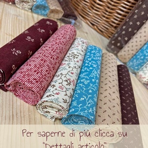 Pode incluir: Uma cole&ccedil;&atilde;o de rolos de tecido em v&aacute;rios padr&otilde;es e cores, incluindo vermelho, marrom, bege e azul. Os rolos de tecido est&atilde;o dispostos em uma pilha sobre uma superf&iacute;cie de madeira. O texto "Per saperne di pi&ugrave; clicca su "Dettagli articolo"" &eacute; vis&iacute;vel na parte inferior da imagem.