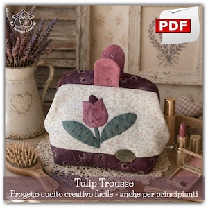 Può includere: Un beauty case trapuntato, il Tulip Trousse, con un motivo floreale e un'applicazione a tulipano. La borsa ha un bordo bordeaux e uno sfondo color crema con un motivo floreale. L'immagine include il testo "PDF" e "Tulip Trousse".