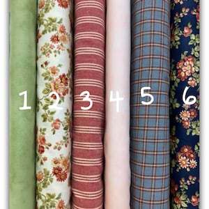 Può includere: Una collezione di sei rotoli di tessuto, ognuno con un motivo e un colore unici. I tessuti includono verde unito, floreale, a righe rosse, rosa unito, plaid blu e floreale su blu navy. I rotoli sono numerati da 1 a 6.