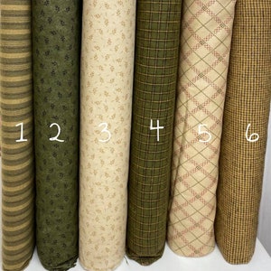 Può includere: Sei rotoli di tessuto in vari motivi e colori. Il tessuto è verde, marrone e beige con motivi a righe, foglie, quadri e rombi. Il tessuto è numerato da 1 a 6.