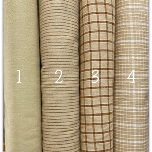 Può includere: Quattro campioni di tessuto in diversi motivi. Il primo campione è di colore verde chiaro uniforme. Il secondo campione ha sottili strisce marroni su uno sfondo verde chiaro. Il terzo campione ha un motivo a quadri marroni e bianchi. Il quarto campione ha un piccolo motivo a quadri bianchi e marroni.