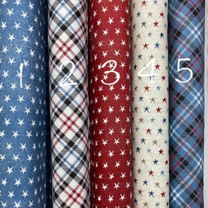 Può includere: Cinque campioni di tessuto con diversi motivi. Il primo campione è un tessuto blu con stelle bianche. Il secondo campione è un tessuto bianco con una trama a quadri rossi e neri. Il terzo campione è un tessuto rosso con stelle bianche. Il quarto campione è un tessuto beige con stelle rosse e blu. Il quinto campione è un tessuto blu con una trama a quadri neri e rossi.