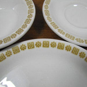 May include: Three white ceramic plates with a brown geometric pattern around the edge. The plates are different sizes.