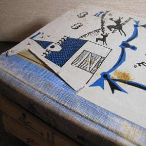 May include: A blue and white book with the title "National Velvet" on the cover. The cover features a blue and white illustration of a house with a chimney and a blue ribbon.