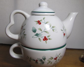 Peut inclure: Ensemble théière et tasse en céramique blanche avec un motif de houx vert et rouge. La théière a un couvercle et une poignée. La tasse a une poignée.