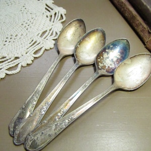 May include: Four silver spoons with ornate designs. The spoons are arranged in a row, with the handles overlapping.
