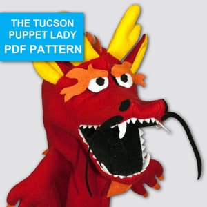 May include: Red felt dragon puppet with a black felt mouth and tongue. The dragon has yellow horns and orange felt flames on its head. The puppet is designed for hand use and has a long black felt tail.