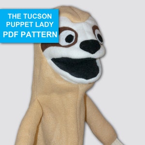Könnte beinhalten: Eine beige Faultier-Puppe mit einem weißen Mund, einer schwarzen Nase und braunen Augen. Die Puppe ist aus weichem Stoff gefertigt und hat eine handförmige Öffnung für die Hand des Benutzers. Die Puppe trägt den Titel "The Tucson Puppet Lady PDF Pattern".