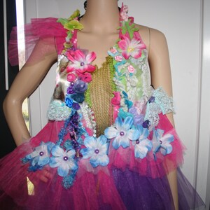May include: A pink and purple tulle dress with a floral bodice. The bodice is decorated with a variety of flowers, including blue, pink, and white. The dress is perfect for a special occasion.