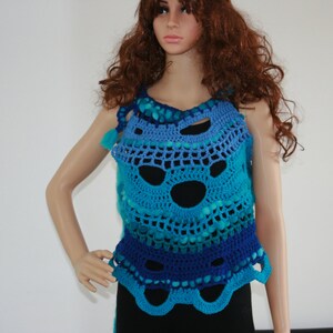 May include: A crocheted top with a blue, teal, and purple ombre design. The top has a loose, flowing fit and features a unique, openwork pattern.