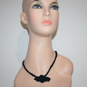 May include: A black necklace with a bat-shaped pendant.