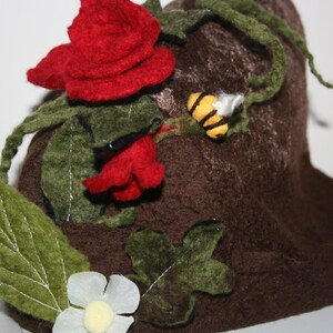 May include: A felt hat shaped like a tree stump with red felt roses, green felt leaves, and a yellow felt bee.
