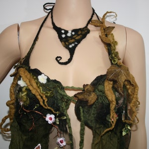 May include: A handmade, nature-inspired halter top and necklace. The top is primarily dark green with brown and yellow accents, featuring felted leaves, flowers, and vines. The necklace is black with white and gold details. The overall theme is fantasy and woodland.
