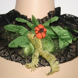 Puede incluir: Un collar de encaje negro con una flor de fieltro verde y naranja.