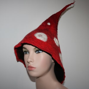 May include: A red felt hat with white felt dots, shaped like a mushroom. The hat has a long pointed crown and a wide brim.