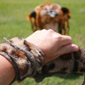 Puede incluir: Un brazalete de piel sintética marrón y negro con un patrón de manchas. El brazalete se lleva en la muñeca de una persona.