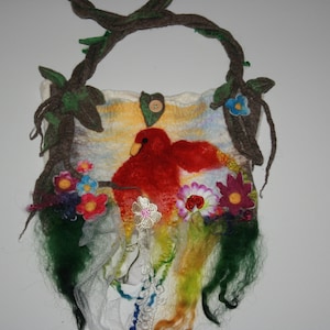 Op de afbeelding: Een vilten wollen tas met een rood vogeltje ontwerp en kleurrijke bloemen. De tas heeft een bruin leren band en is versierd met groene bladeren.