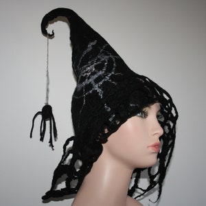 May include: A black felt witch hat with a spider web design and a dangling spider. The hat has a long, pointed crown and a wide brim.