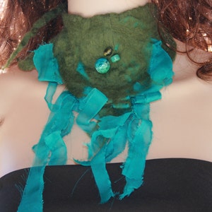 May include: A green felt necklace with turquoise blue fabric accents and green and blue gemstone embellishments.