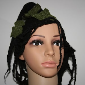 May include: A black wig with long, braided strands and green felt leaves woven into the top.