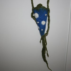 May include: A blue knitted pouch with white polka dots hanging from a green cord. The pouch is cone-shaped and has a long green cord.