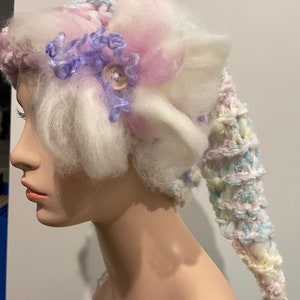 Fairytale knitted pixie hat.Made from my hand spun art yarn.Adorned with large fluffy Merino wool flower.Made with love,wool and imagination