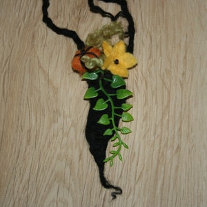 Peut inclure: Un serre-tête en feutre noir avec une fleur en feutre, deux citrouilles en feutre et des feuilles en feutre vert attachées.