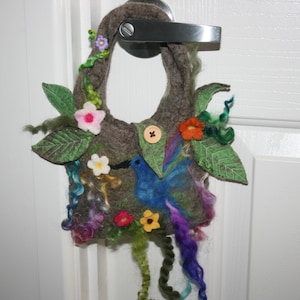 May include: A brown felt bag with a bird, flowers, and leaves. The bag has a button closure and is decorated with colorful felt embellishments.