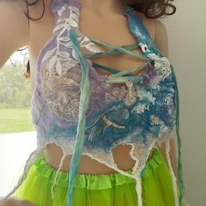 Peut inclure: Un haut halter bleu, violet et blanc avec des détails en dentelle et un motif de libellule. Le haut est noué avec des rubans bleus et verts et a un bord effiloché.