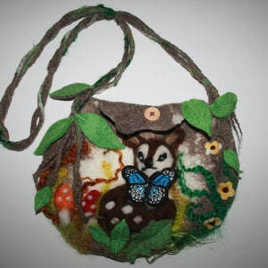 Op de afbeelding: Een bruine handtas van vilt met een hert- en vlinderontwerp. De tas heeft een groen vilt blad- en wijnstokontwerp en een bruine knoopsluiting.