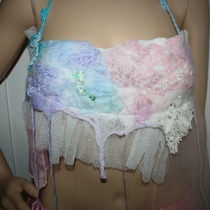 May include: A delicate, pastel-coloured top made of felted fabric and lace. The top features a layered design with a pink, blue, and white colour scheme. The fabric is soft and flowing, and the lace adds a touch of elegance.