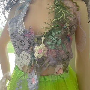 May include: A purple and green floral top with lace and embroidery. The top is made of a soft, flowing fabric and features a variety of floral designs, including roses, leaves, and vines. The top is perfect for a summer wedding or a special occasion.