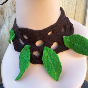 May include: A brown felt necklace with a cut-out design and green felt leaves attached.