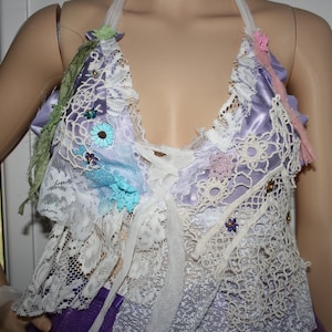 May include: A white lace halter top with a lavender satin lining and colourful floral embellishments.