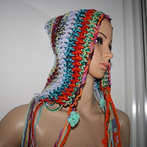 Puede incluir: Una bufanda con capucha de ganchillo de colores con largos flecos. La bufanda está hecha con una variedad de colores, incluyendo rojo, naranja, amarillo, verde, azul y morado.