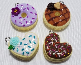 May include: Four handmade polymer clay donut charms with different toppings and sprinkles. The donuts are in the shape of a circle and a heart. The charms are ready to be added to necklaces, bracelets, or keychains.