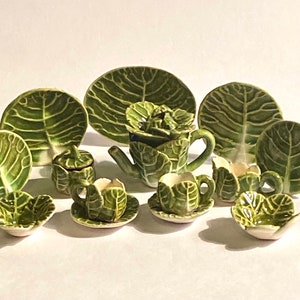 May include: A miniature tea set with a cabbage leaf design. The set includes a teapot, creamer, sugar bowl, four cups, and four saucers.