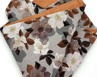 May include: A grey and white floral pocket square with a brown and orange trim. The floral pattern features white flowers with brown centres and brown leaves.