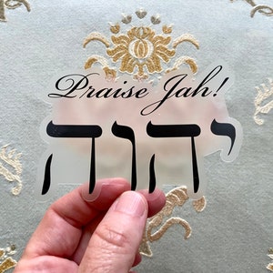 Pode incluir: Um adesivo transparente com as palavras "Praise Jah!" e a palavra hebraica para "Jah" em letras pretas.