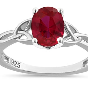 May include: A sterling silver ring with a red oval gemstone set in a Celtic knot design. The ring is marked "925" on the inside band.