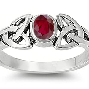 May include: A silver ring with a red gemstone set in a Celtic knot design.