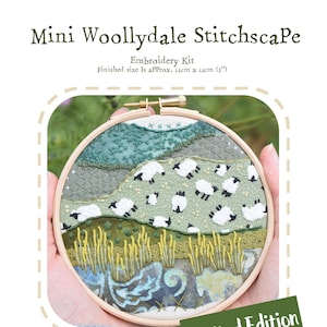 May include: A limited edition embroidery kit featuring a green and white landscape with sheep. The kit includes a calico base fabric, patterned cotton fabrics, embroidery threads, cotton lace, an embroidery hoop, and a printed template and instructions. The finished size is approximately 12cm by 12cm.