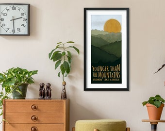 Könnte beinhalten: Ein gerahmter Druck mit einer grünen und gelben Berglandschaft und dem Text "YOUNGER THAN THE MOUNTAINS GROWIN' LIKE A BREEZE".